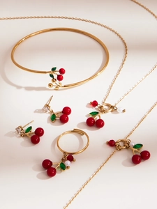 Detail van kersensieradenset met ketting armband ring en oorbellen in gouden finish
