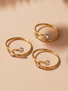 Dettaglio di tre anelli in acciaio placcati oro 18k con scintillanti zirconi 5A di qualità