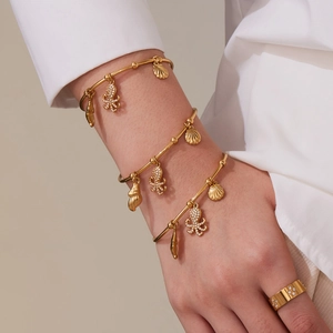 Golden ocean charm bracelets featuring zircon octopus and shell pendants on model wrist