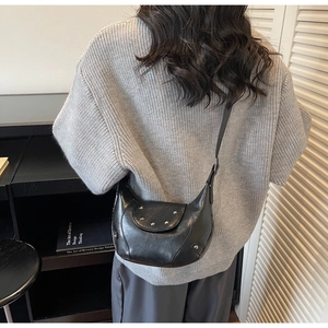 Détail du sac croissant noir avec des clous argentés et une texture de cuir poli brillant
