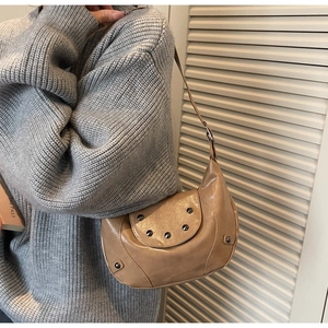 Detail of vintage beige hobo bag with silver studs worn with a knit sweater