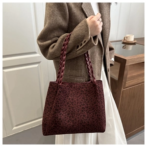 Detail of burgundy leopard print tote bag with woven shoulder strap in a chic setting