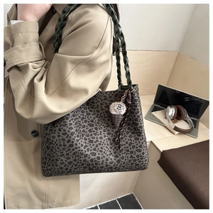 Detalle del bolso de leopardo con asas tejidas verdes y colgante decorativo de helado