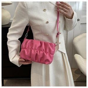 Borsa a nuvola increspata rosa vivace indossata a spalla con un elegante abito bianco