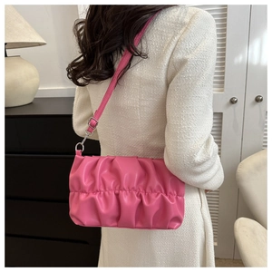 Modella che indossa una borsa cloud plissettata rosa con chiusura argento e tracolla