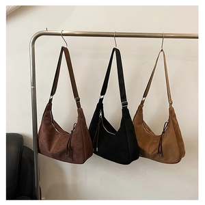 Close-up of hobo shoulder bags in brown, black, and camel suede with tassel details