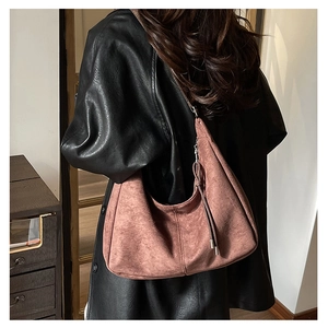 Dettaglio borsa Hobo in camoscio rosa con nappe laterali e texture vintage raffinata