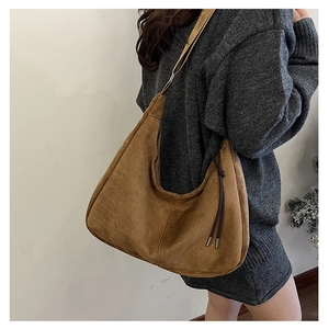 Detailed view of a brown suede hobo bag with fringe tassels and a wide shoulder strap