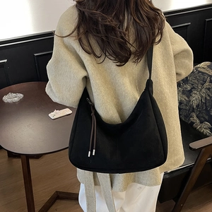 Minimalist black faux suede crescent bag with wide shoulder strap shown on model
