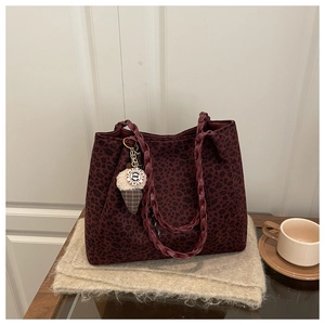 Detalle del bolso de leopardo granate con asas trenzadas y colgante decorativo