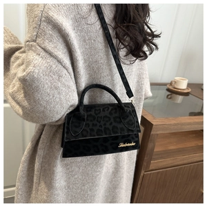 Détail du sac bandoulière léopard noir avec logo doré et texture douce en fausse fourrure