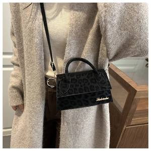 Détail du petit sac bandoulière léopard avec logo doré sur cardigan en maille beige