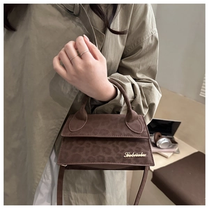 Détail d'un mini sac à bandoulière léopard marron avec logo doré sur texture suède
