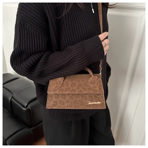 Détail d'un sac bandoulière léopard marron avec logo doré et texture en daim doux