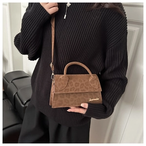 Détail du sac bandoulière léopard avec logo doré et texture en daim doux