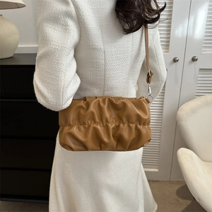 Borsa a nuvola plissettata caramello con tracolla indossata da modella in interno moderno