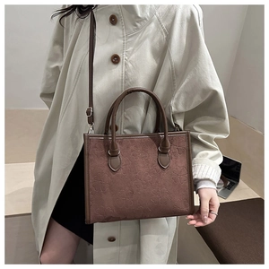 Detail of brown suede tote bag with clover embossing and adjustable shoulder strap