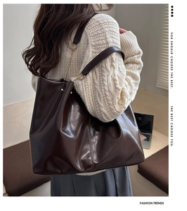Detail of soft leather tote bag in dark coffee with golden chain and metallic hardware