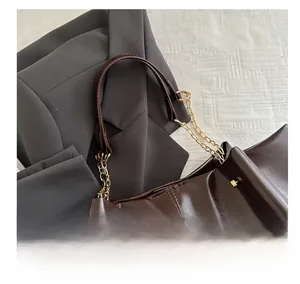 Detail of dark brown glossy leather tote with mixed gold chain and leather shoulder strap
