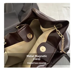 Macro view of golden magnetic closure and chain detail on dark brown leather tote bag