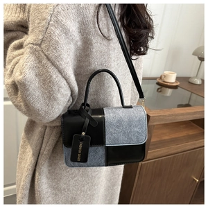 Detailed view of color-block crossbody bag featuring contrast leather and felt textures