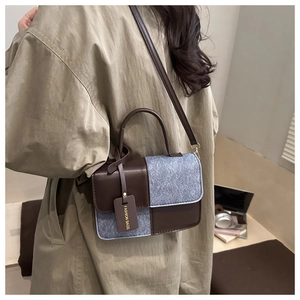 Detail of contrast stitch handbag with premium brown leather and grey felt texture