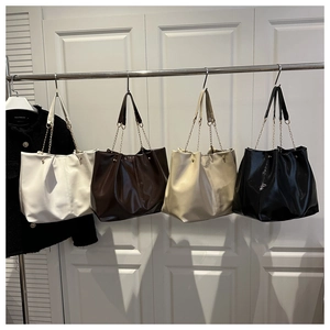 Detail of four large leather tote bags in white, brown, cream and black with chain straps
