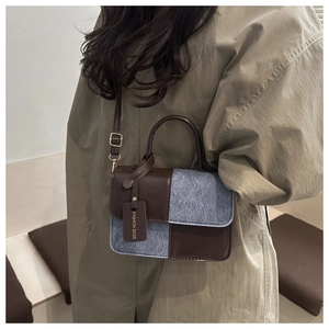 Detail of contrast-color crossbody bag showing leather and wool fabric texture blend