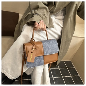 Detail of a chic patchwork crossbody bag featuring brown leather and grey denim textures