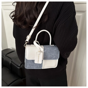 Detail of color-block crossbody bag with denim and white leather worn by a model