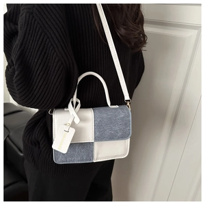 Detail of color-block crossbody bag with denim texture and white leather handle