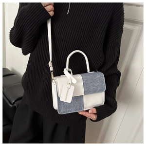 Detail view of a color-block crossbody bag styled on a model with white leather handle