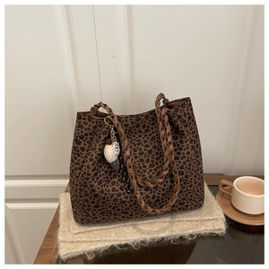 Detalle de bolso tote de leopardo con asas trenzadas y adorno de peluche decorativo