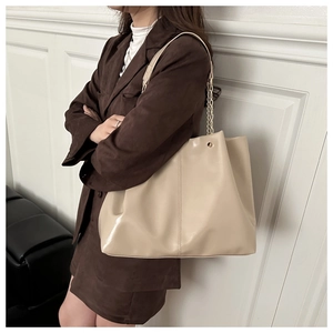 Detail view of large cream tote bag with chain strap on model in minimalist setting