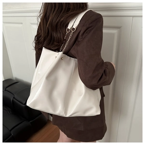 Detailed side view of large white soft leather tote bag with gold chain strap on model