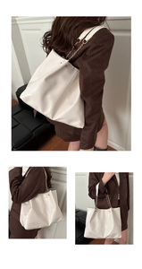 Detail view of large cream leather tote bag featuring glossy finish and metal chain straps