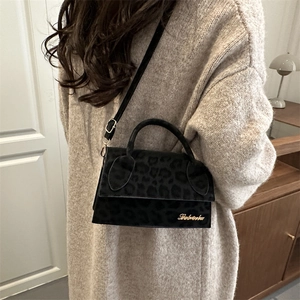 Sac bandoulière tendance à motif léopard avec logo doré porté par un mannequin chic