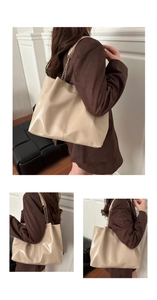 Close-up of beige tote bag showing glossy texture and metal chain shoulder strap detail