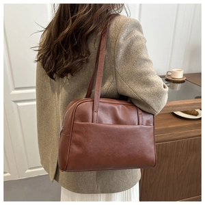 Detail of vintage brown leather shoulder bag featuring side metal zipper and front pocket