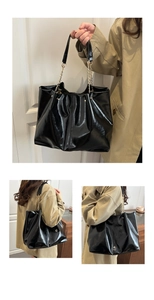 Detail of black patent leather tote bag featuring pleated design and gold chain strap