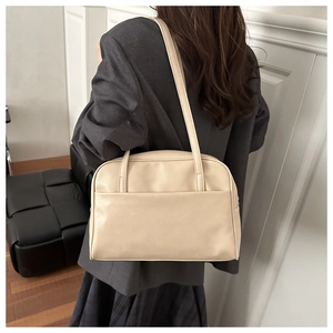 Detail of minimalist beige tote bag with wide front pocket and slim shoulder straps