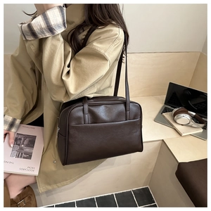 Detail of a vintage dark brown faux leather tote bag worn by a model in a city setting