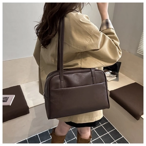 Detail of dark brown leather tote bag with slim shoulder straps in a cafe setting