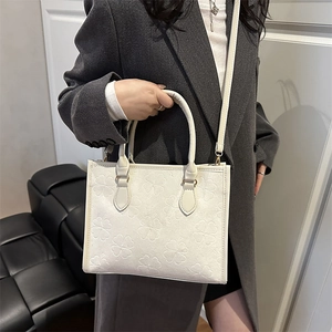 Elegant white clover embossed tote bag with gold hardware and adjustable strap