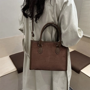 Brown vintage tote bag with clover embossing and adjustable strap on a female model
