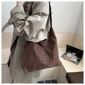 Close-up of a leopard print tote bag with brown trim styled in a modern office setting