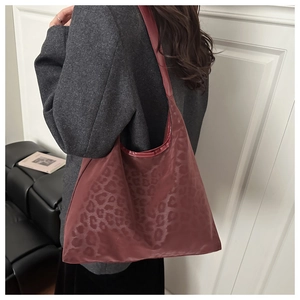 Side view of trendy burgundy leopard print tote bag worn on a woman's shoulder