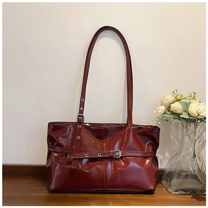 Détail du sac à main en cuir verni bordeaux avec boucles métalliques de style vintage