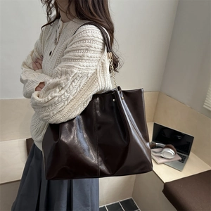Deep brown oversized tote bag in high-gloss leather with chain strap for office commute