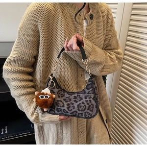 Detail of leopard print hobo bag with a stylish chain and bear plush charm accessory